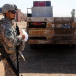 Spc. Edwin Ronquillo, an Iraqi Transportation Network security escort with the 699th Maintenance Company stands by as an Iraqi flat bed is loaded for an ITN convoy, at the central receiving and shipping point Sept. 30 at Joint Base Balad, Iraq. A key aspect of the Iraq withdrawal challenge will be the determination of what equipment will go where and to whom. The cost of the Iraqi drawdown, including training for Iraqis, will be significant. Added to this is the question of what equipment can and will be transferred within the region, including to Afghanistan, and which equipment to transfer to the United States. The cost over two years of such a transition will run into the tens of billions.<br />Credit: 13th Sustainment Command (Expeditionary), 9/30/09 Managing Iraq Withdrawal