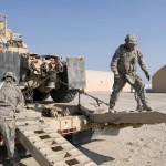 Third Army Soldiers Sgt. Eric Baldonado and Staff Sgt. Joseph Calderon of the 1404th Transportation Company unchain and prepare to remove a Heavy Equipment Transport truck from an M-1000 Trailer at the "Drop and Swap" station of the 180th Transportation Battalion Truck Rodeo at Camp Arifjan, Kuwai. The timed competition tested two-person teams in six of the most common difficulties faced on the road. Units taking place in the event make regular trips into Iraq to get heavy equipment, much of which will be refurbished to support future operations in Afghanistan. <br /><em>Credit: Third Army/U.S. Army Central PAO, 12/4/09, Location: Camp Arifjan, Kuwait</em> US Army Drop and Swap