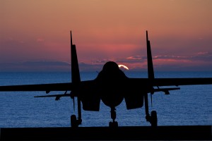 Silhouette of military attack aircraft against vibrant sunset sk