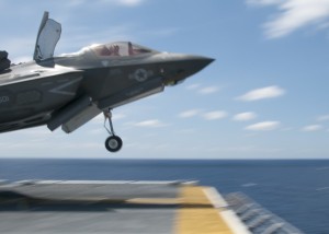 150522-N-BQ308-110 ATLANTIC OCEAN (May 22, 2015) As fast as its name, an F-35B Lightning II screams past a flight deck handler as it takes off during flight operations aboard the amphibious assault ship USS Wasp (LHD 1). Wasp, with VMFA-121 and VMFAT-501 embarked, is underway conducting the first phase of operational testing for the F-35B Lightning II aircraft, which will evaluate the full spectrum of F-35B measures of suitability and effectiveness in an at-sea environment. (U.S. Navy photo by Chief Mass Communication Specialist William Tonacchio/Released)