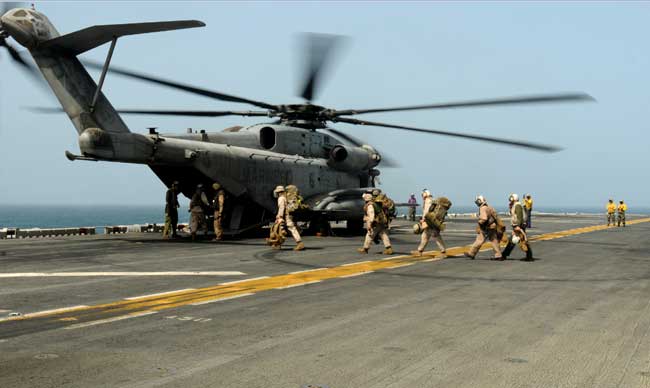 Marines prepare to board a Marine Corps CH-53E Super Stallion assigned to Helicopter Marine Medium “White Knights” on board USS Peleliu. This group is the first wave to go ashore in Pakistan to help maintain the heavy lift aircraft the Navy and Marine Corps are providing to deliver relief supplies to flood-stricken regions. (Credit Photo: USN Visual Service, August 12th, 2010)